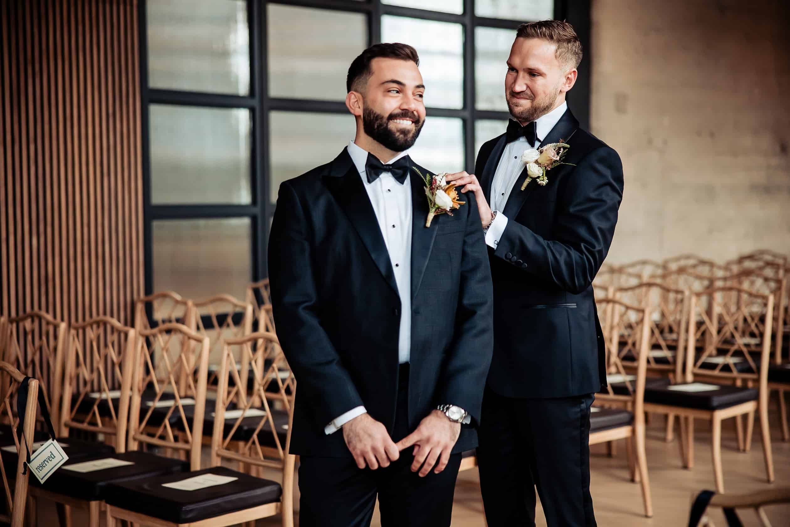 Photo of a candid moment between two grooms during their wedding reception